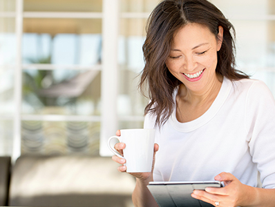 Woman drinking coffee while using iPad