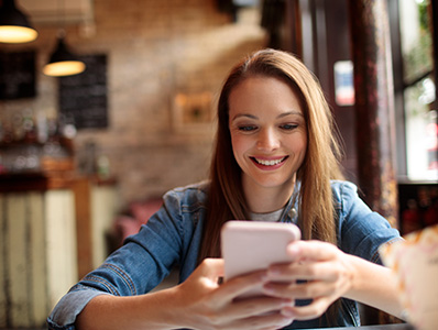 Woman at a cafe smiling and looking at her phone