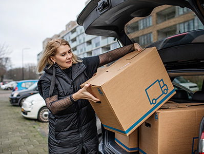 Woman packing moving boxes into the back of a car