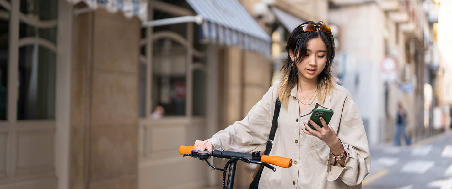 Women on phone while holding scooter
