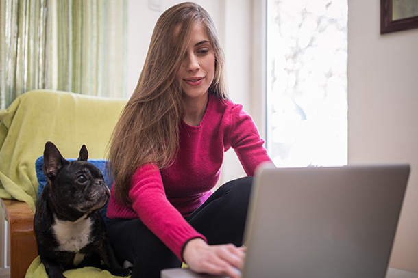 Woman with her dog working on a laptop