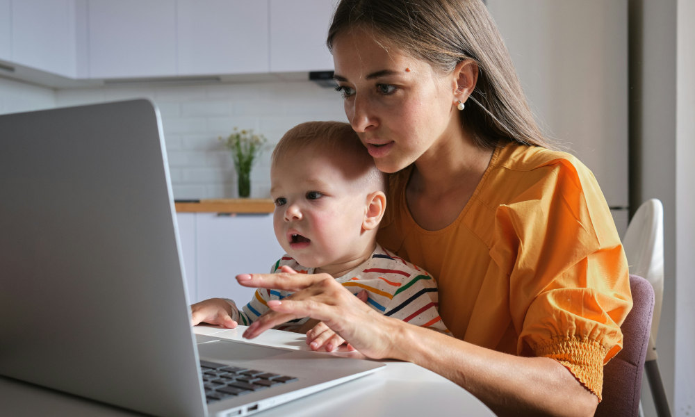 Young mother reviewing her finances with her infant on her lap.