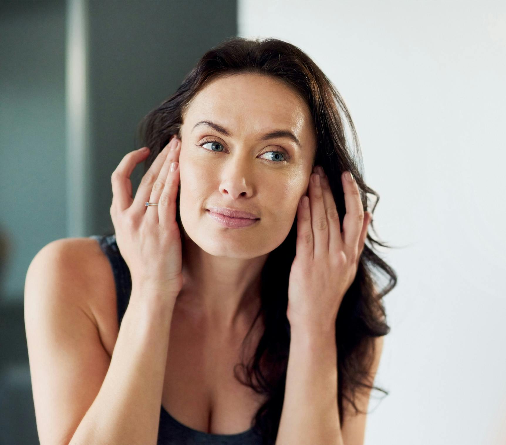 woman looking at her face in mirror
