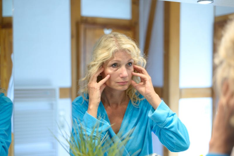 An older blonde woman looking in the mirror