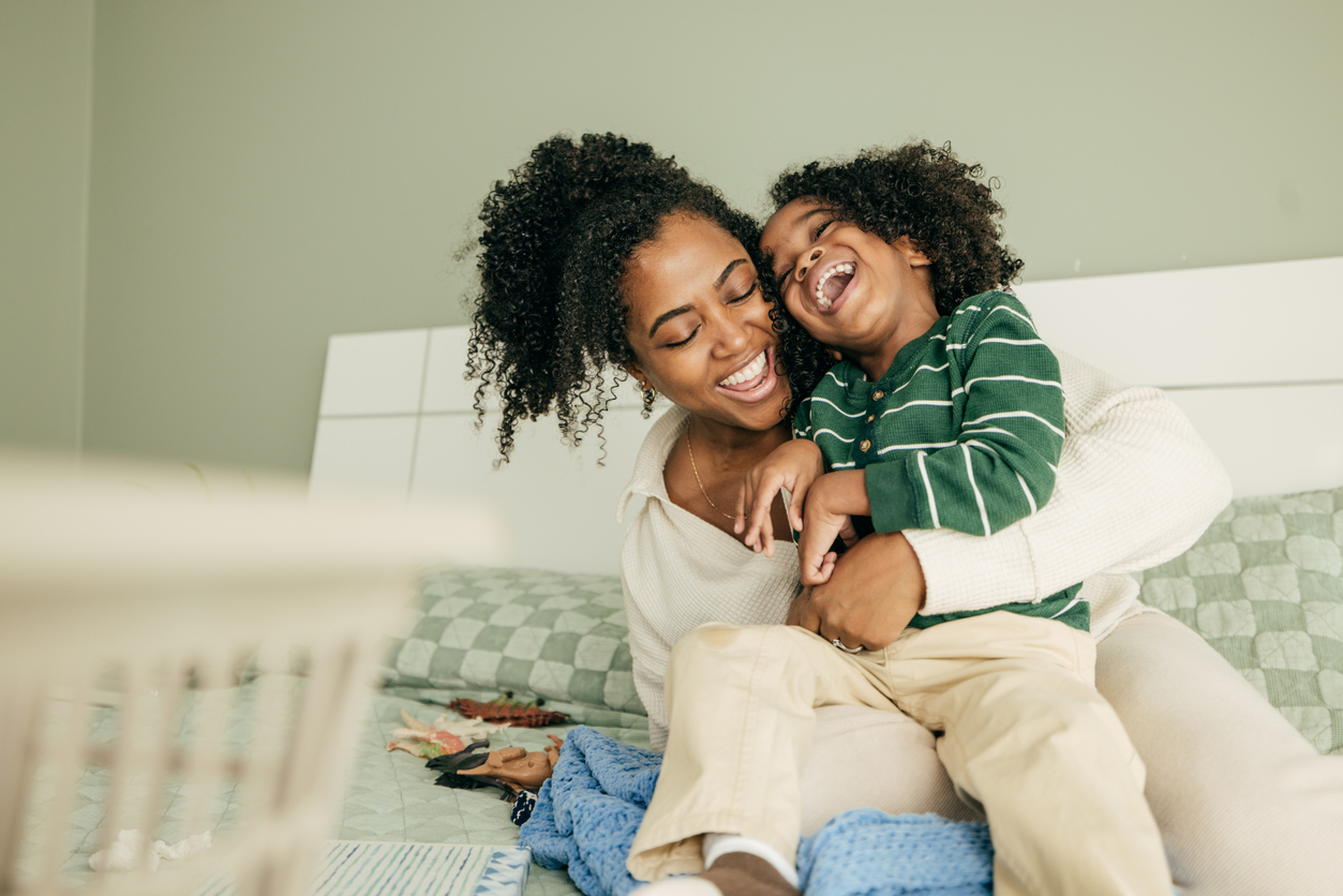 Mother smiling and laughing with young child while sitting together.