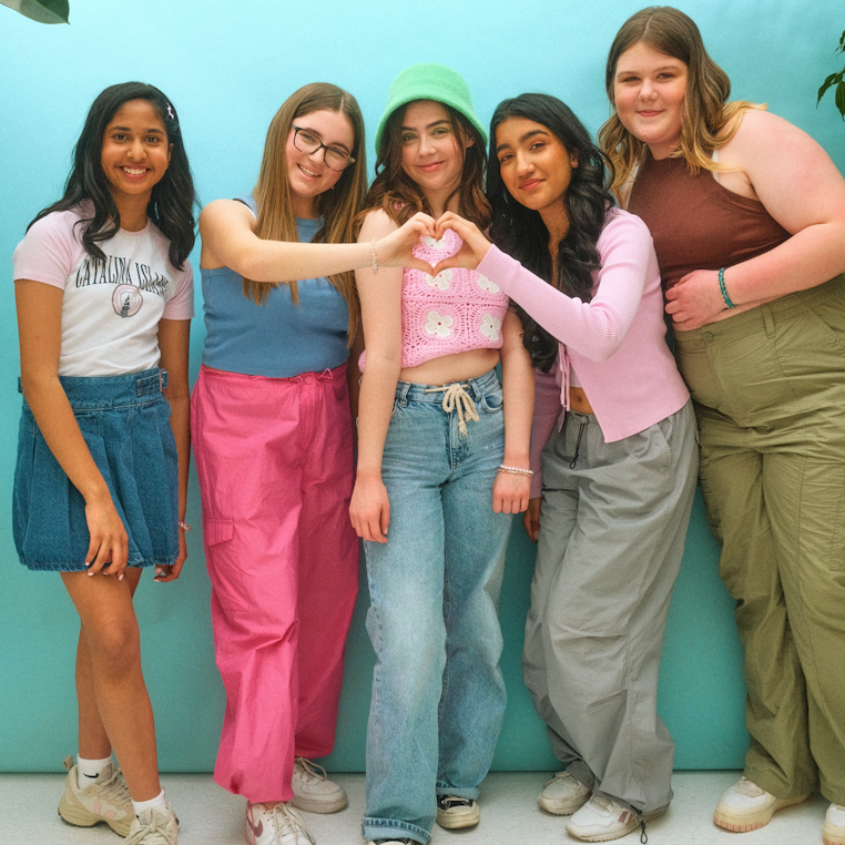 group of 5 teen girls giving a heart gesture to the camera