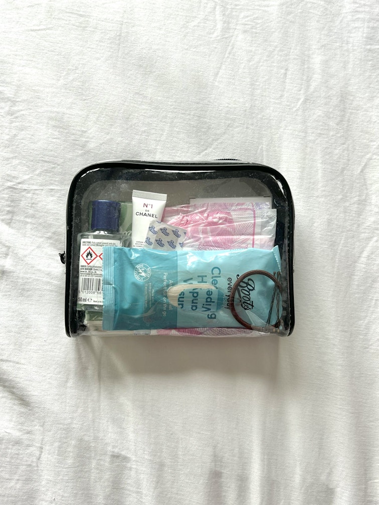 A clear toiletry bag holds period pads, wipes, a hand sanitiser, and skincare products.