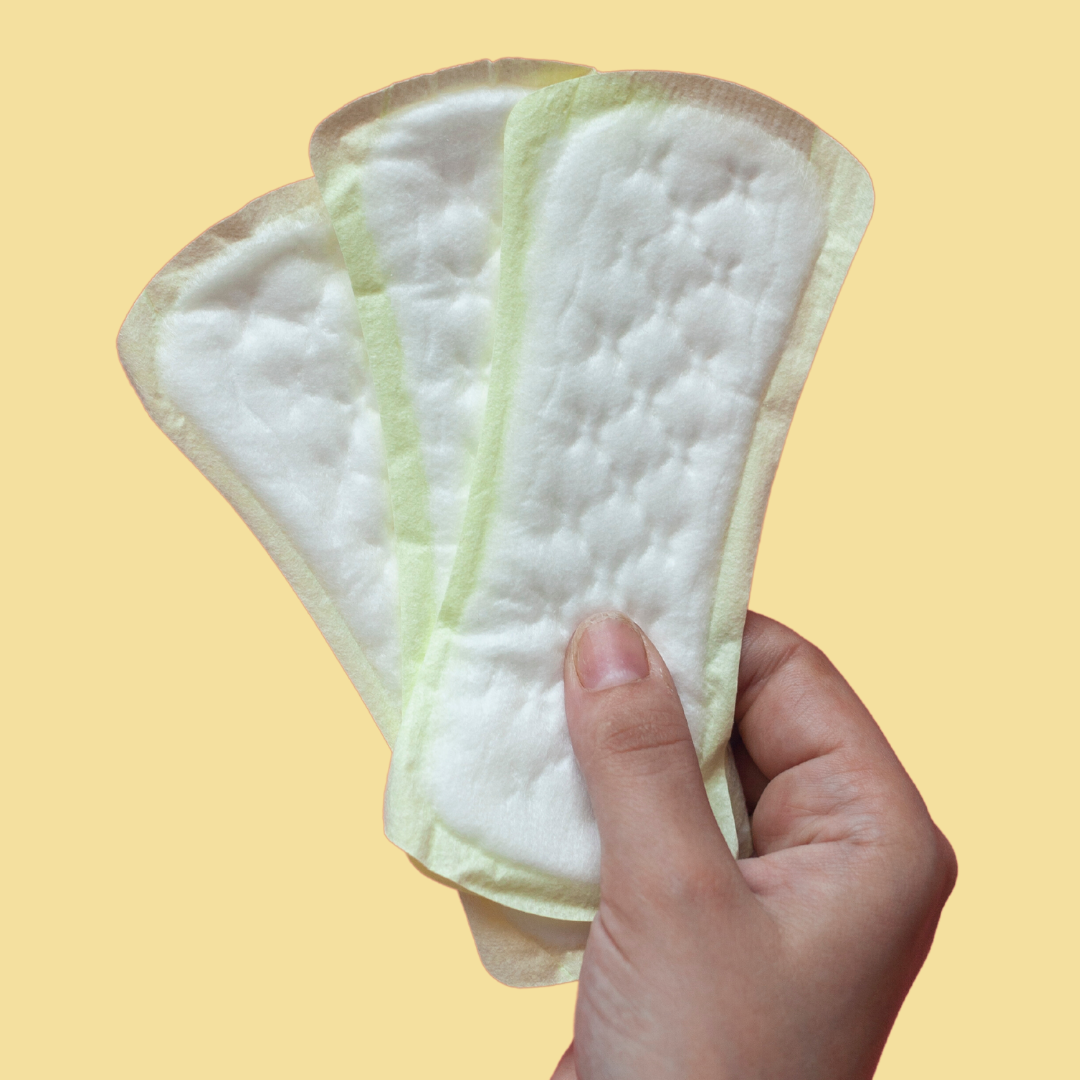 A hand holding a fan of three panty liners against a yellow background.
