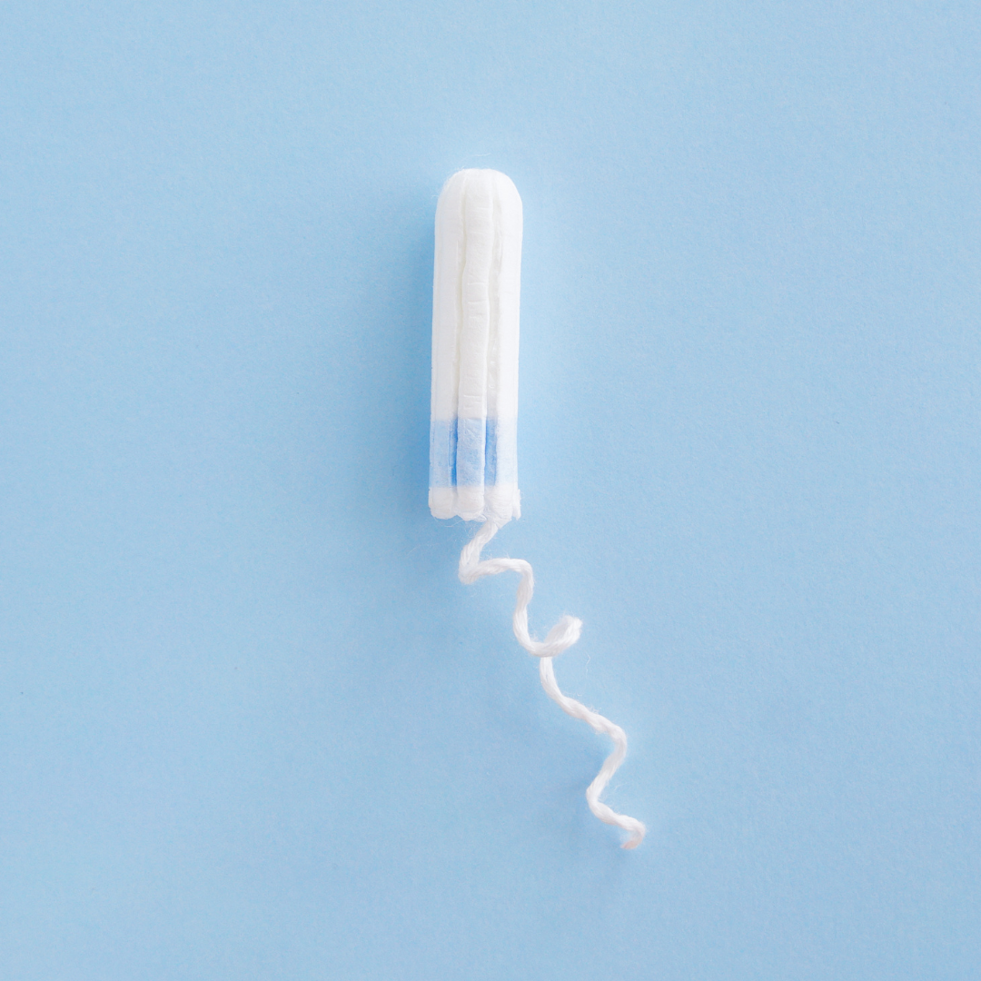 A single tampon with a curled white string sits on a plain light blue background.