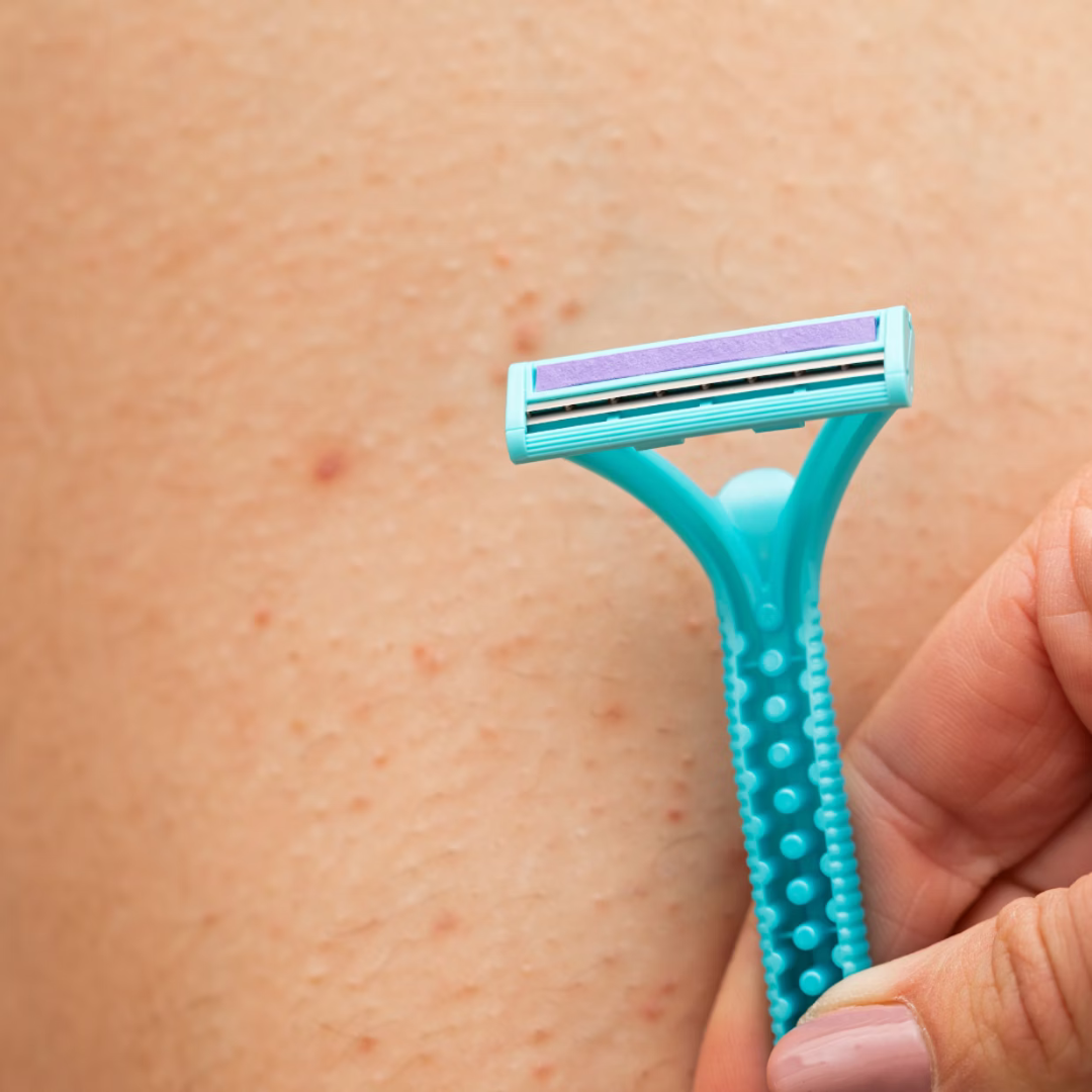 Close-up of a hand holding a teal razor against bare skin on a leg.