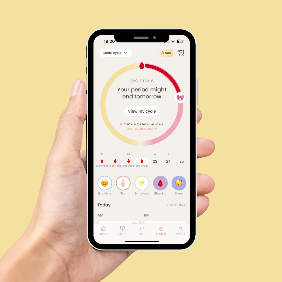 Hand holding a phone showing the luna app's period tracker with cycle day, phase, and a calendar view of upcoming days.