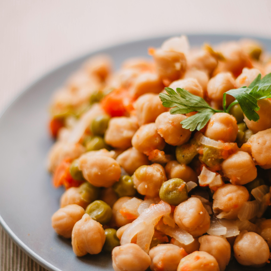 A plate of chickpeas, peas, and onion garnished with fresh parsley.