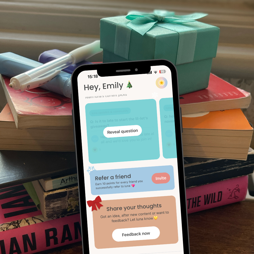 Phone showing the luna app home screen next to a wrapped gift box and books