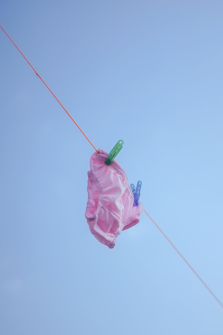 Pink underwear pegged to a washing line against a clear blue sky.