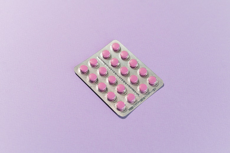 Blister pack of pink contraceptive pills laid diagonally on a lilac background.