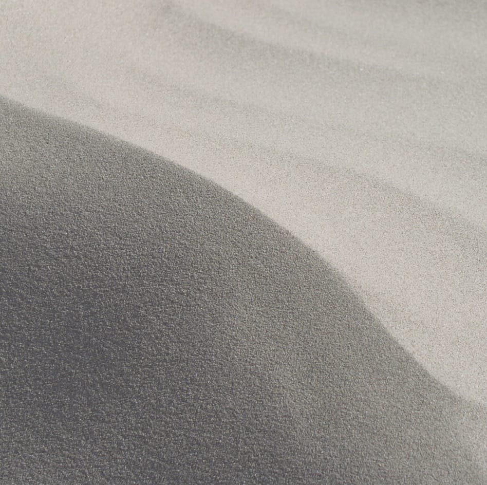 Close up of sandy beach with shadow cast on it