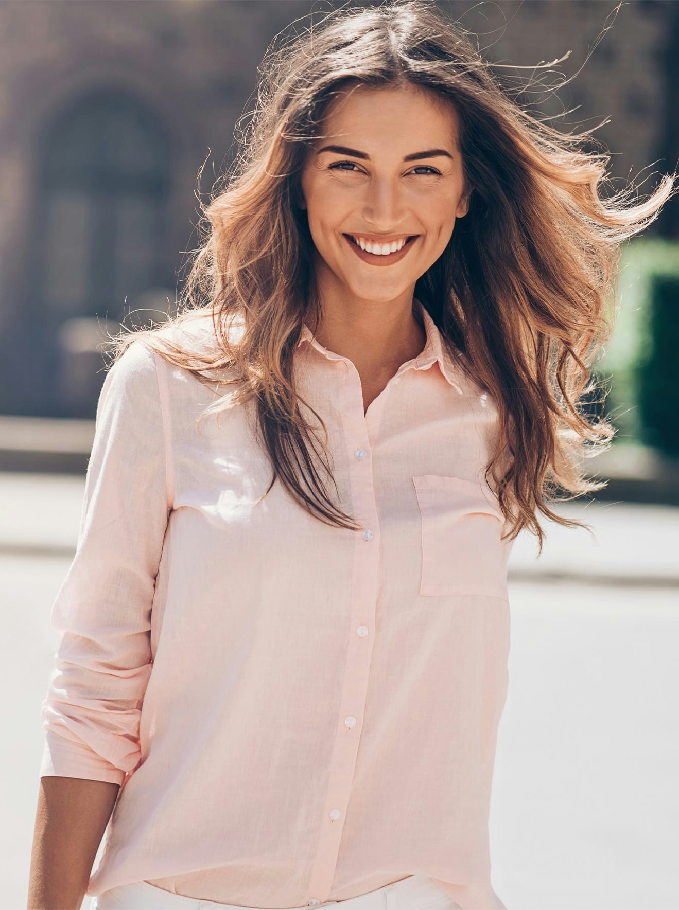 Woman in pink button up smiling outside