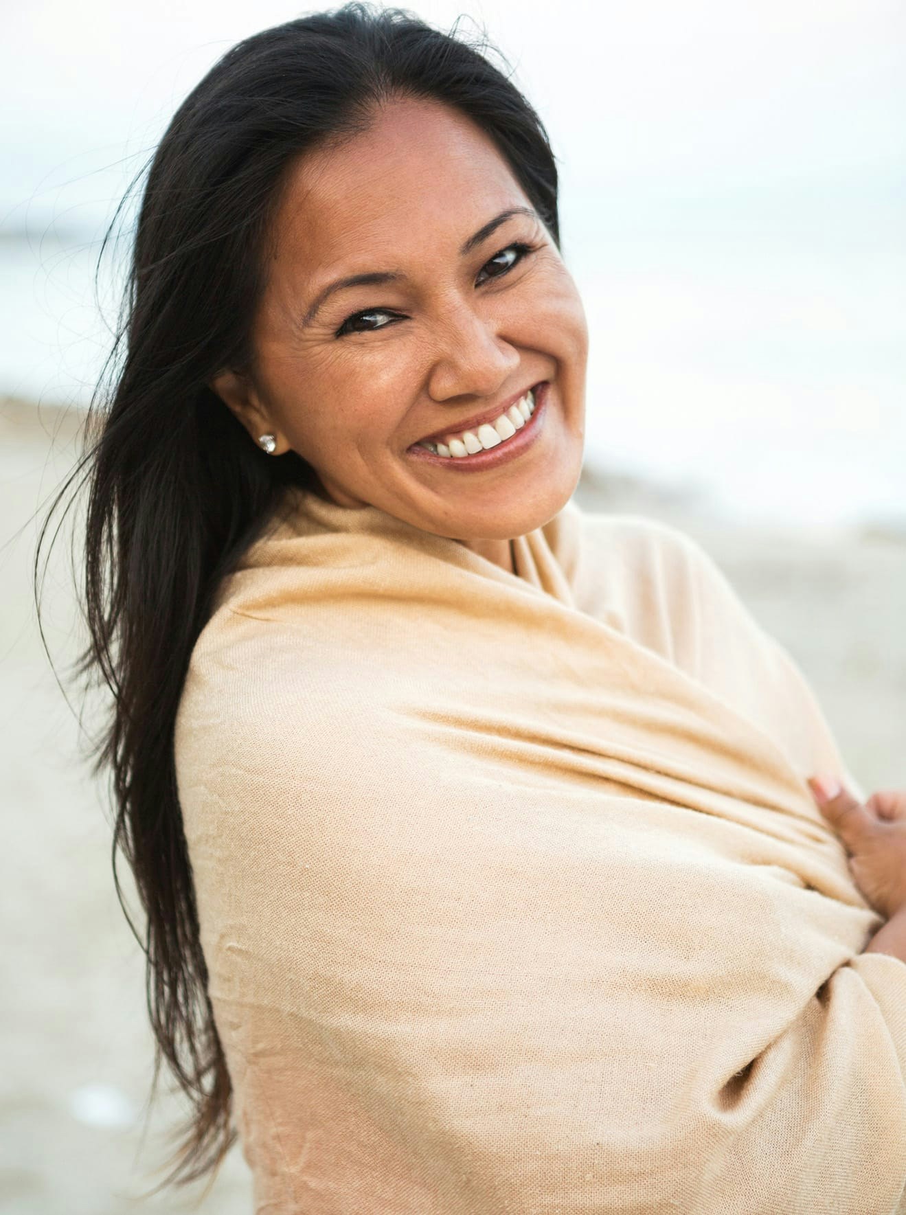Woman with shawl smiling on beach
