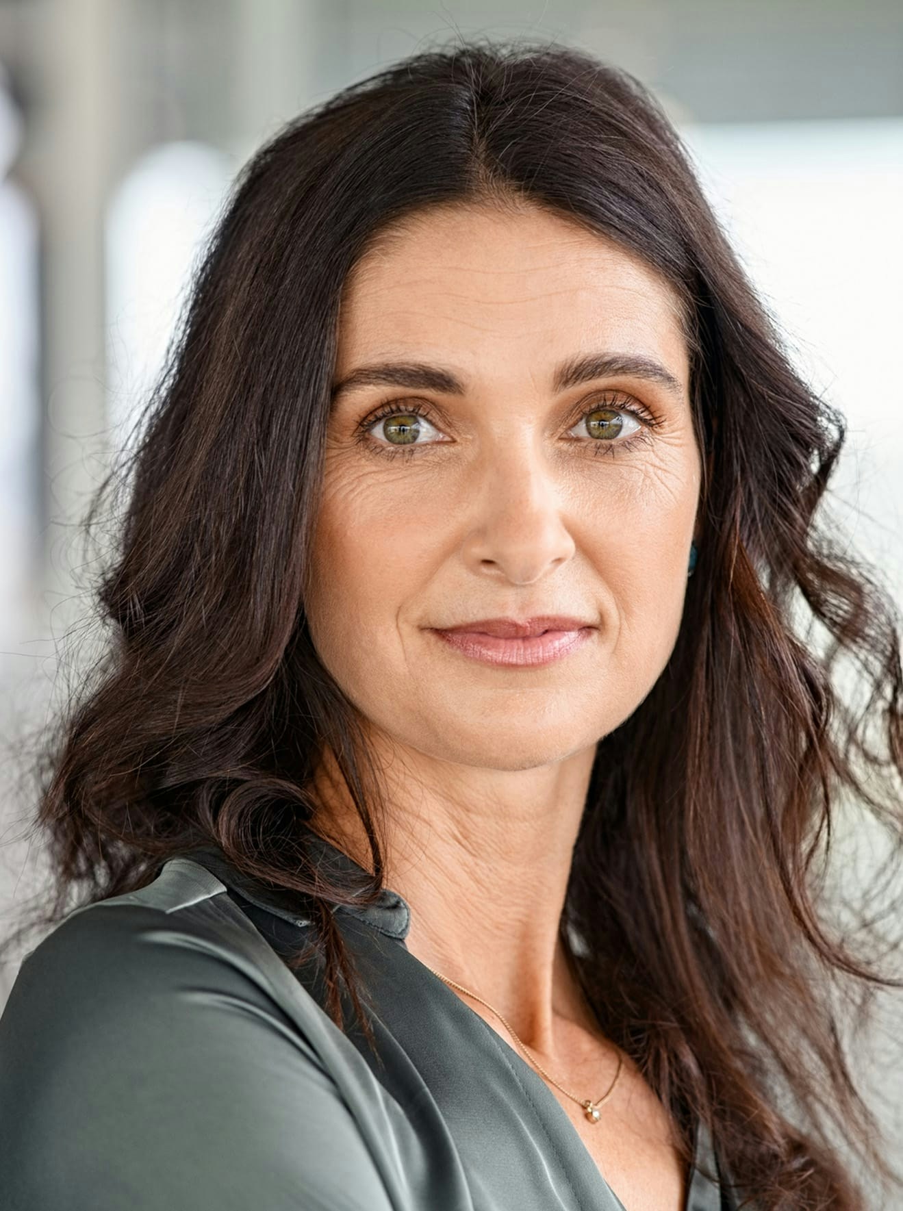 Woman in olive blouse posing for picture