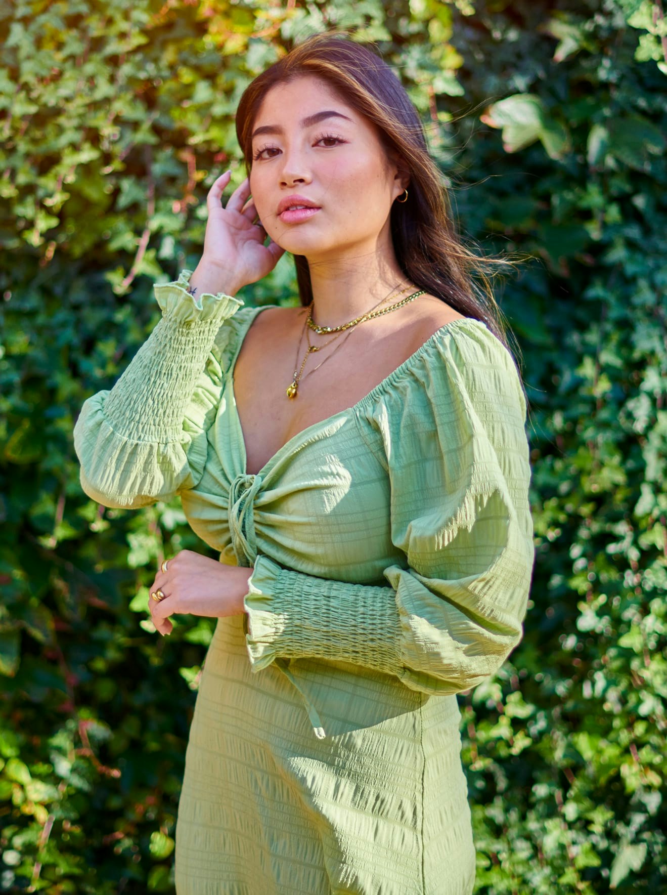 Woman in green dress standing in front of an ivy wall