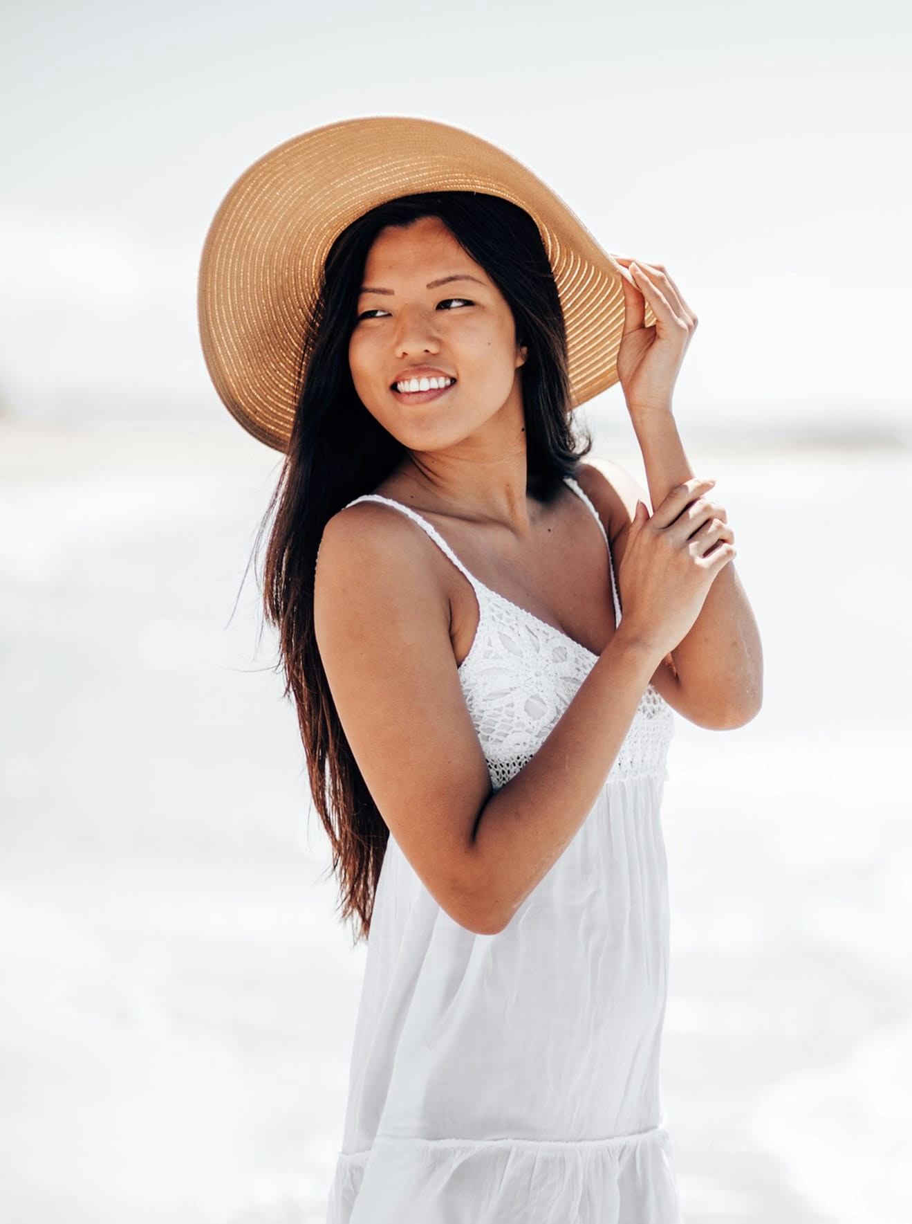Woman in white dress and sun hat on beach