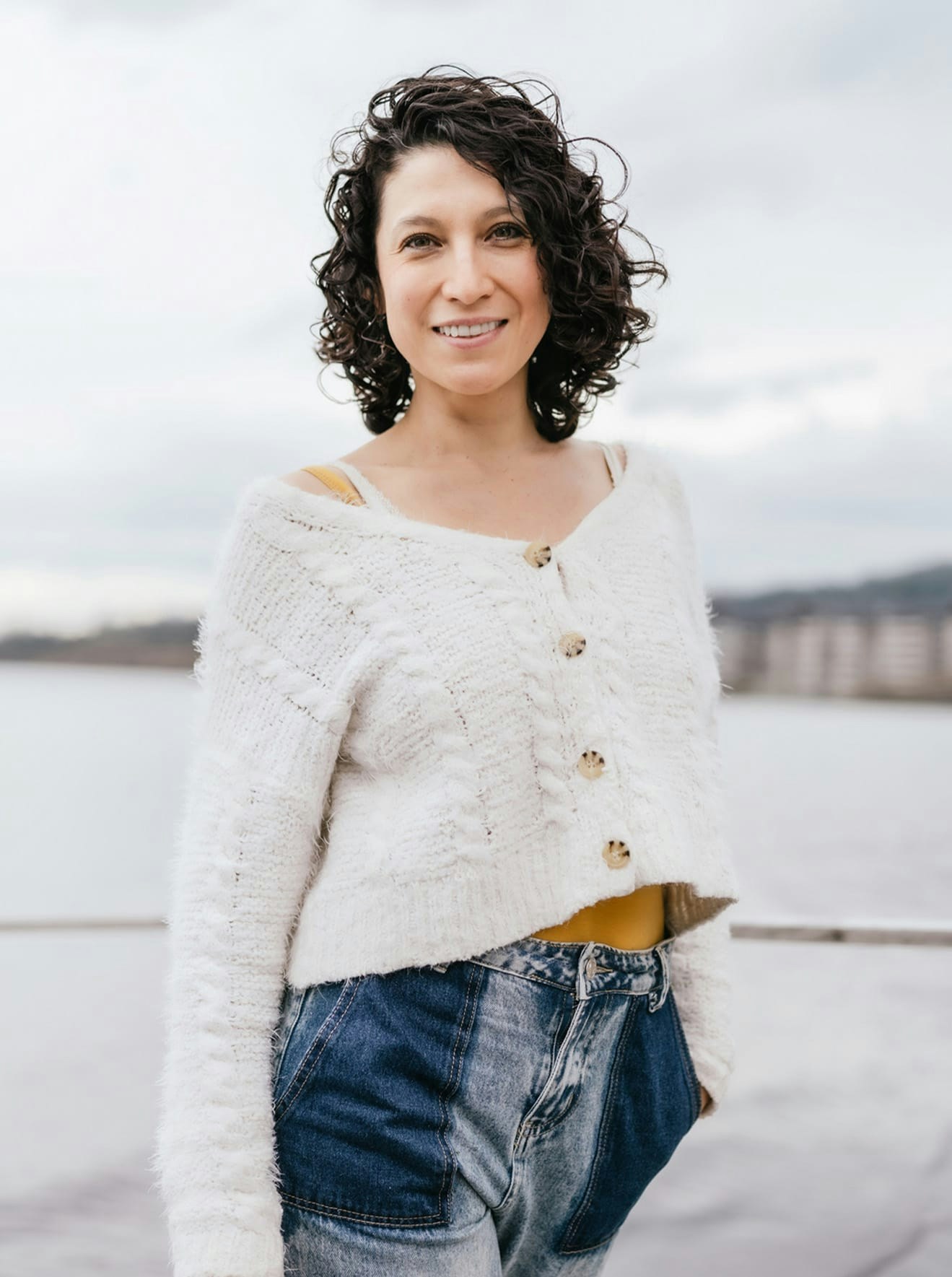 Woman in white sweater and jeans smiling