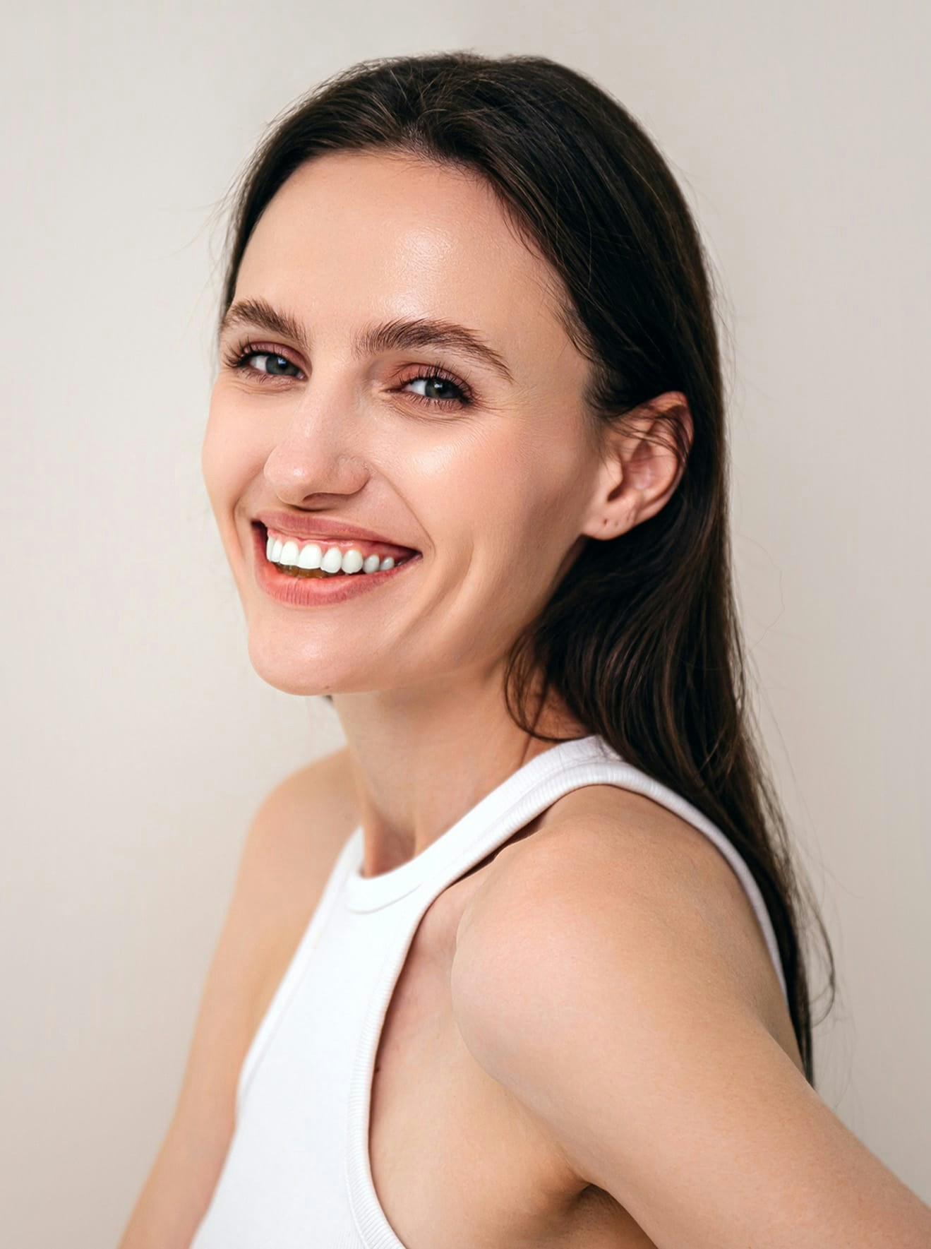 Woman in white tank top smiling for photo