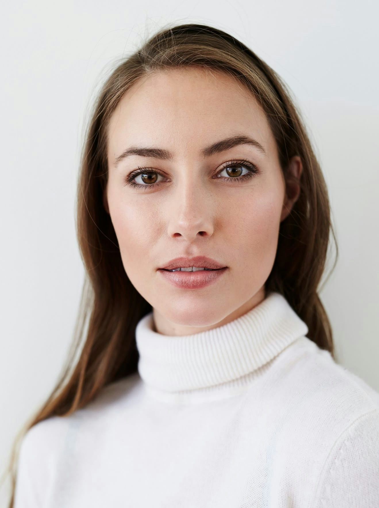 Woman in white turtle neck posing for picture