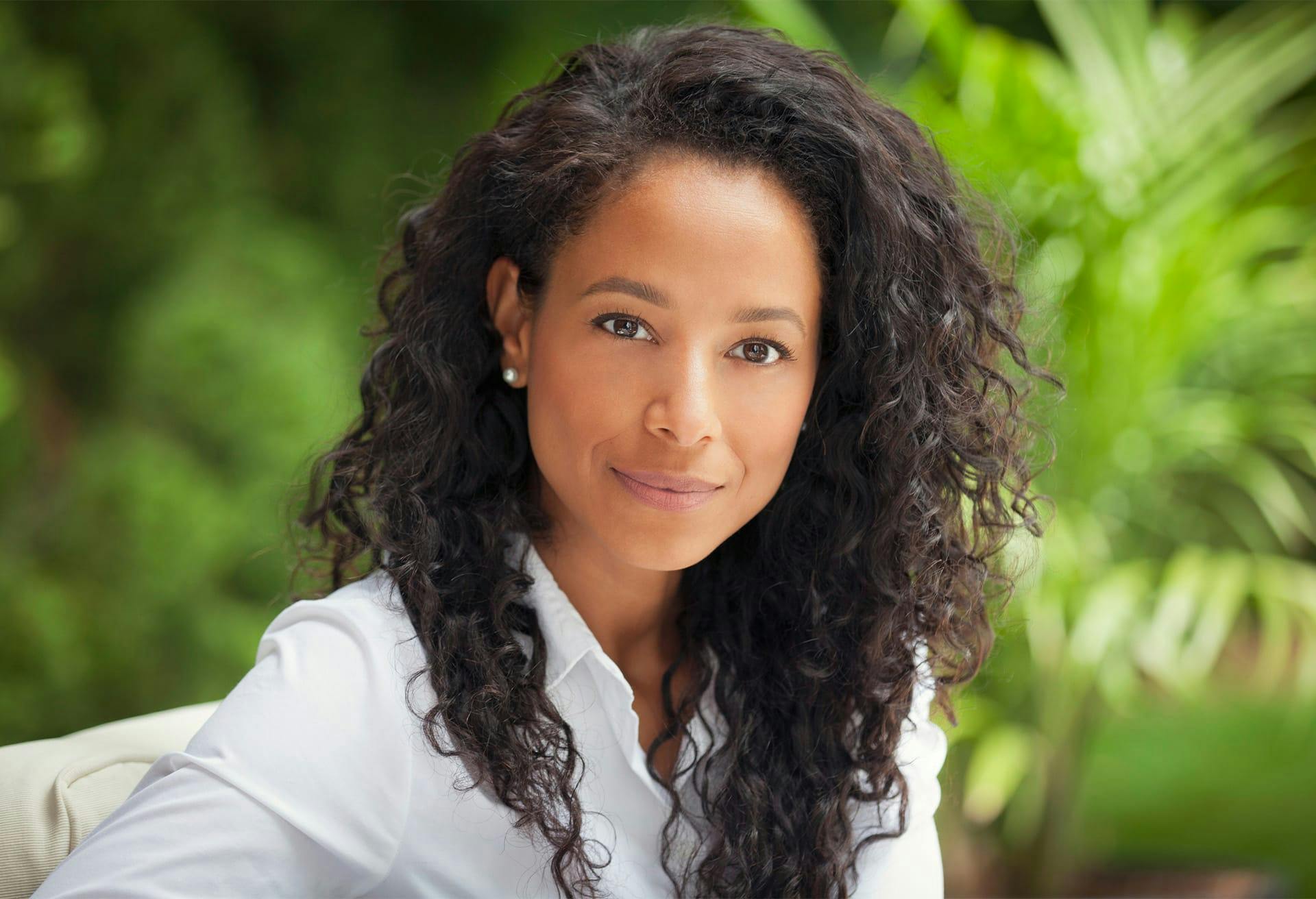 Woman in white shirt in front of bushes