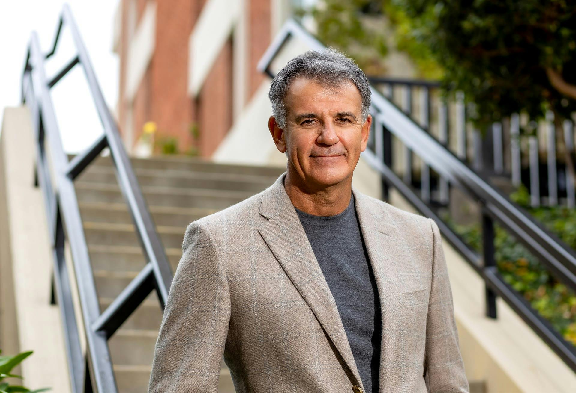 Dr. Glynn Bolitho in blue shirt and blazer on stairs