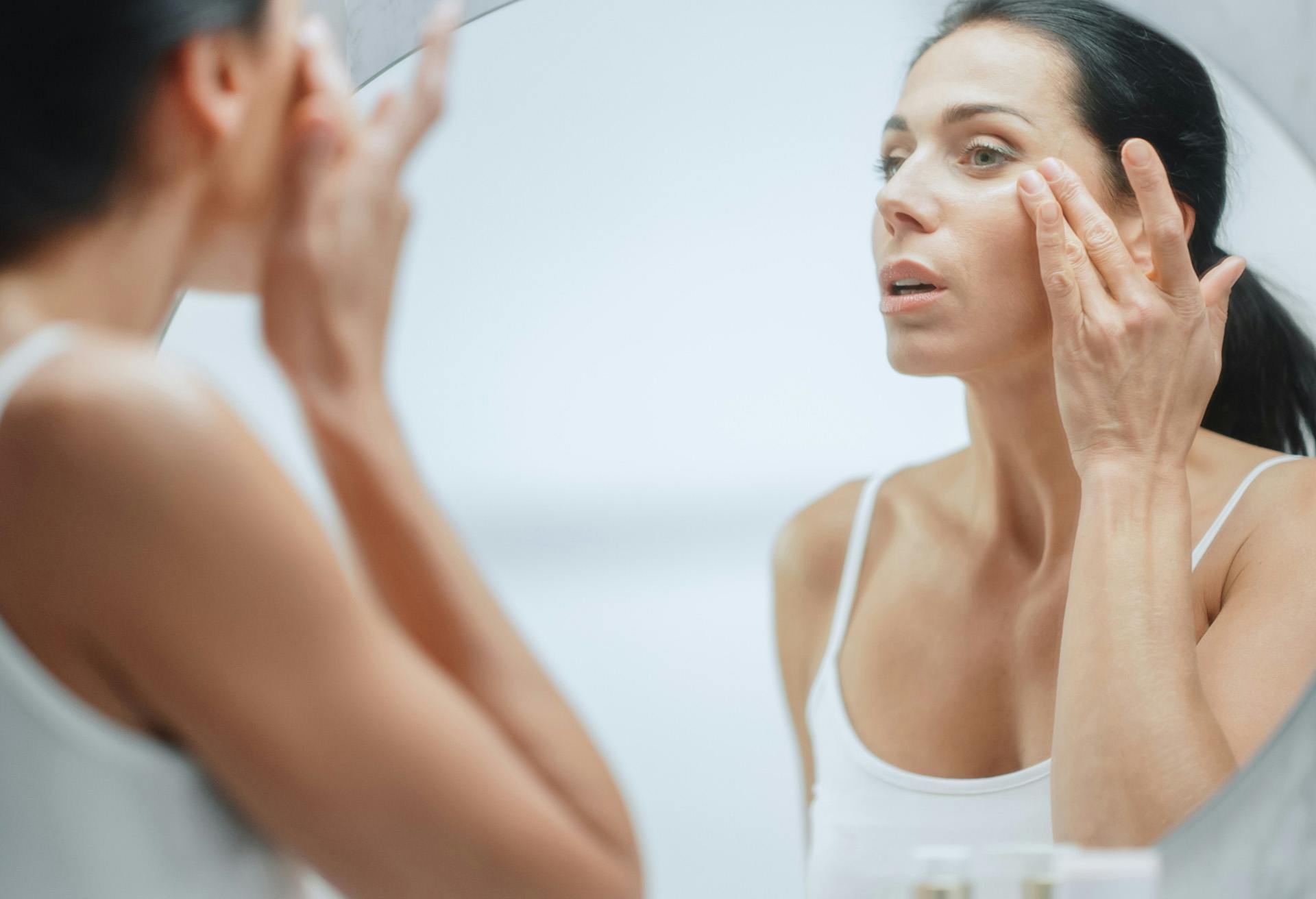 Woman applying skincare products to face