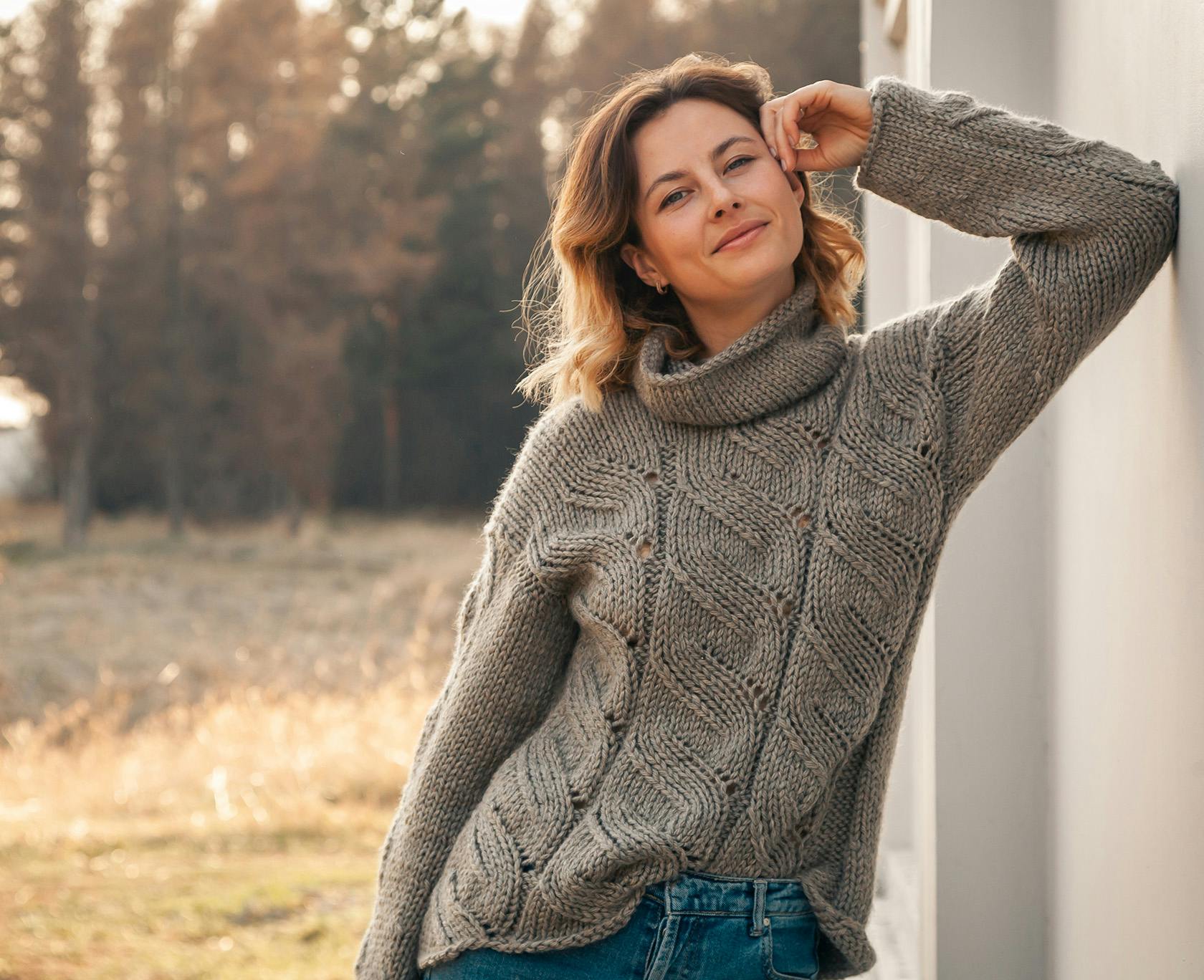 woman leaning against a wall in a field