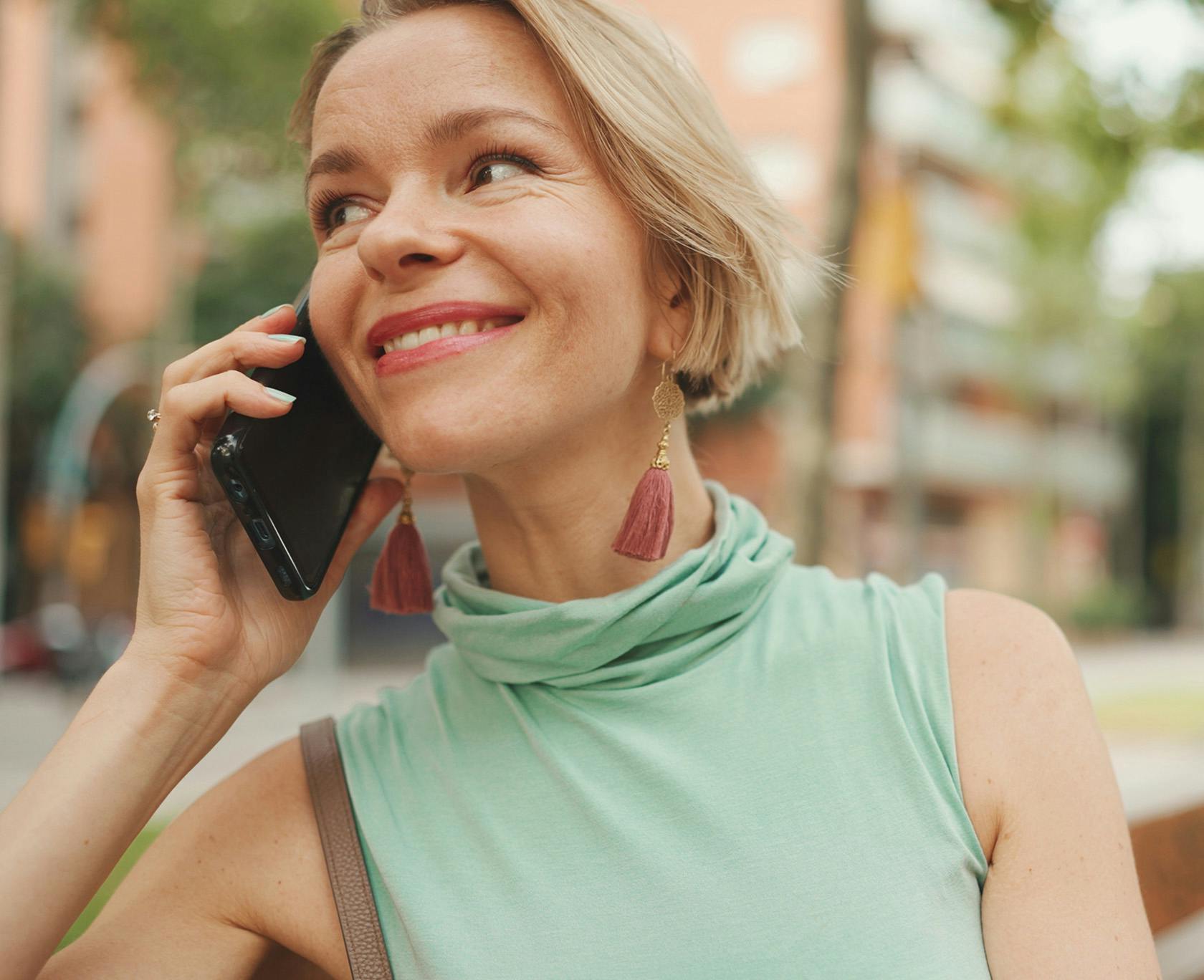 blond woman talking on cell phone in urban setting with buildings in background