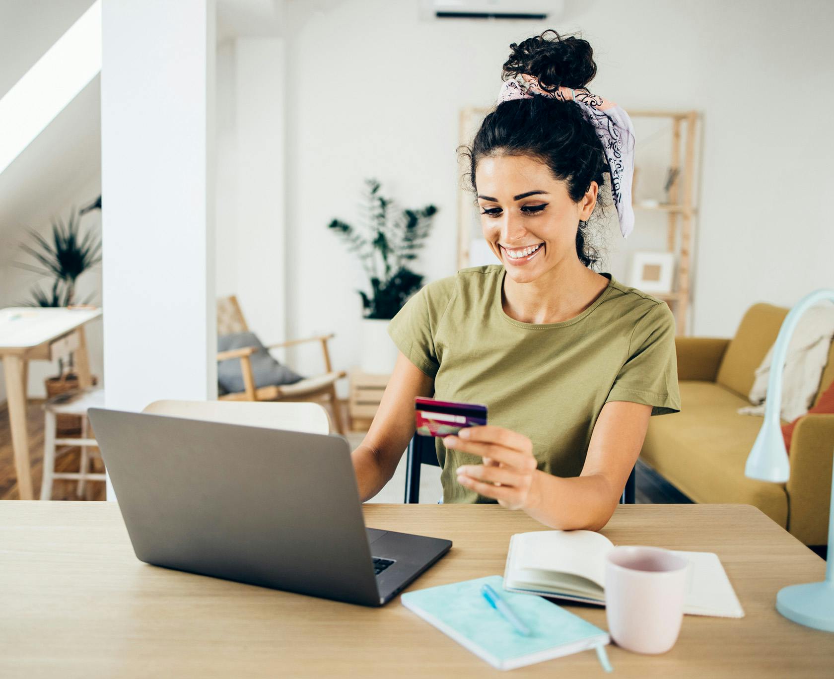 woman sitting at a table with a laptop and a credit card