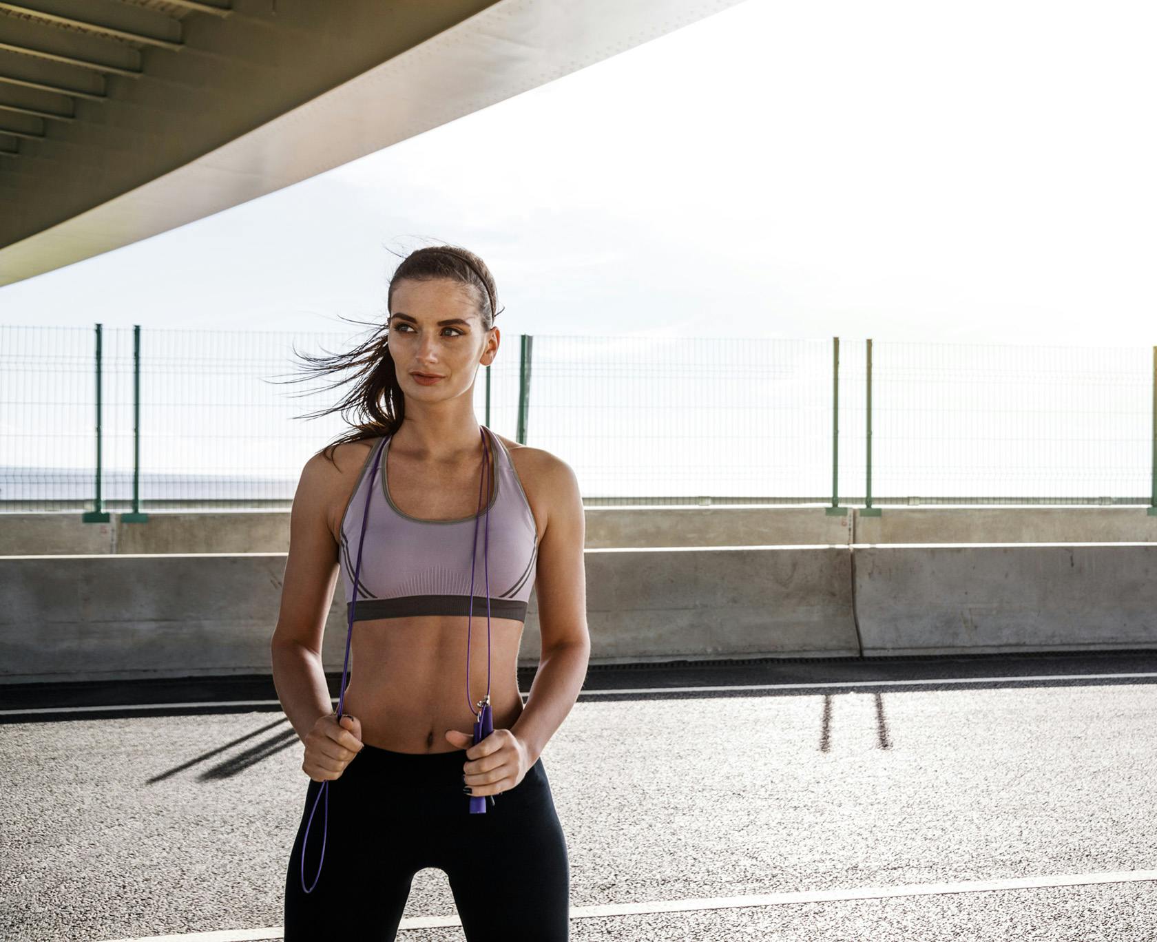 a woman standing on a road with a jump rope