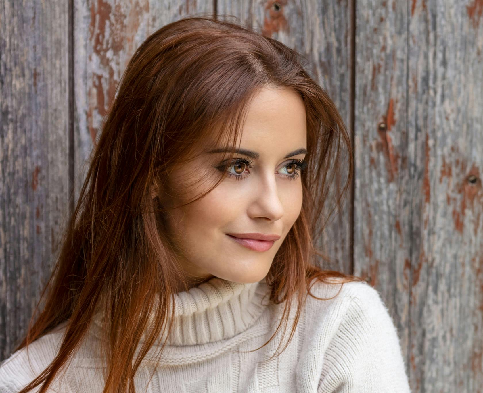 woman with long red hair and a turtleneck sweater