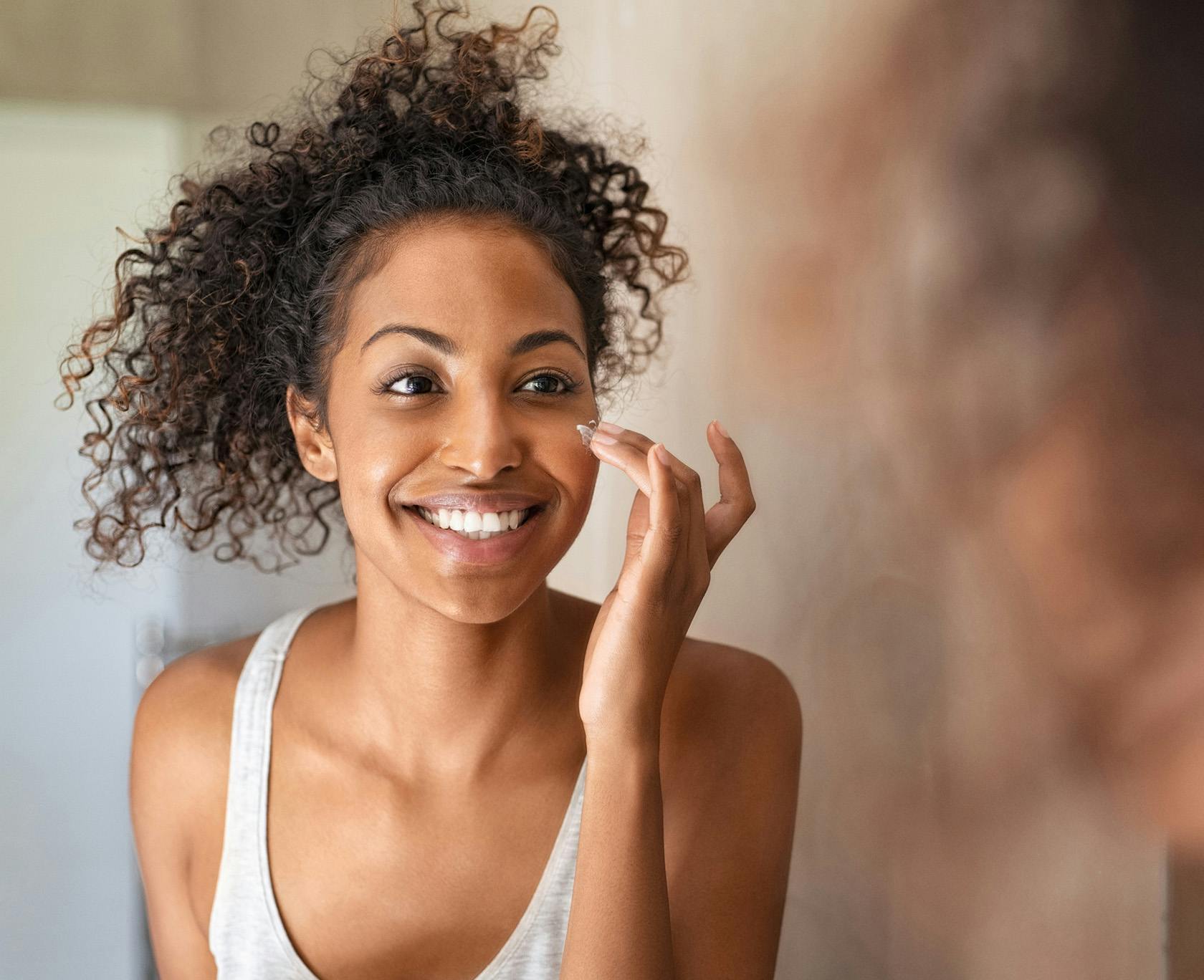 smiling woman with curly hair looking at herself in mirror