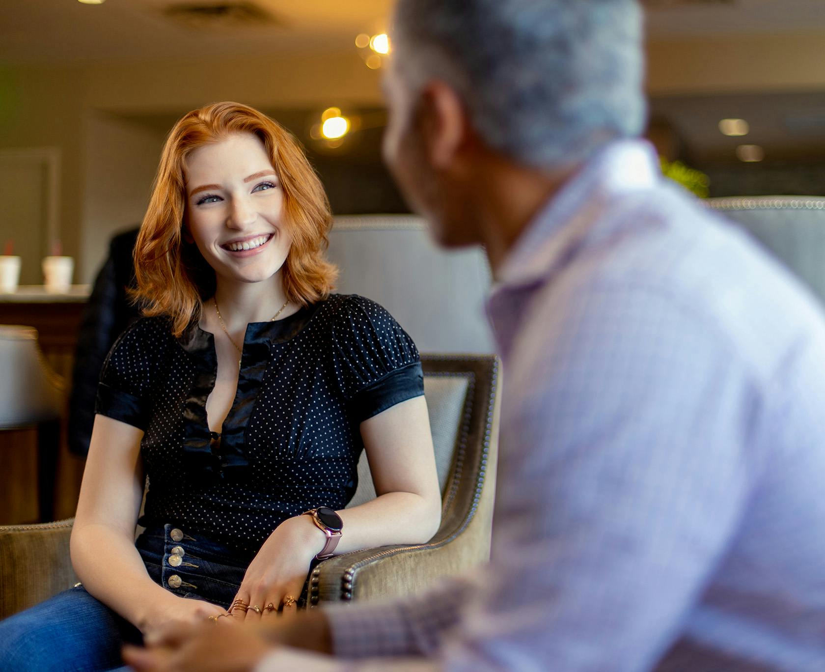 orange haired smiling woman at Lavie Institute sitting in chair with man in background