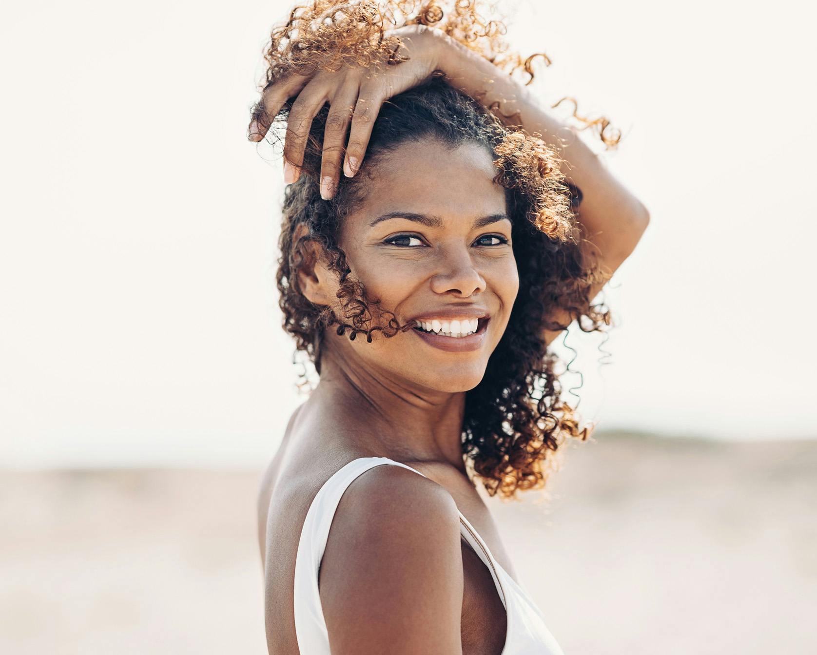 Woman with her arm over her head smiling