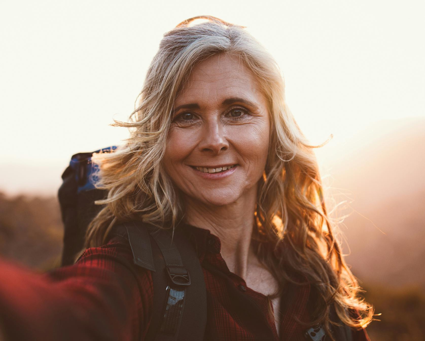 smiling woman taking a selfie with her camera in the mountains