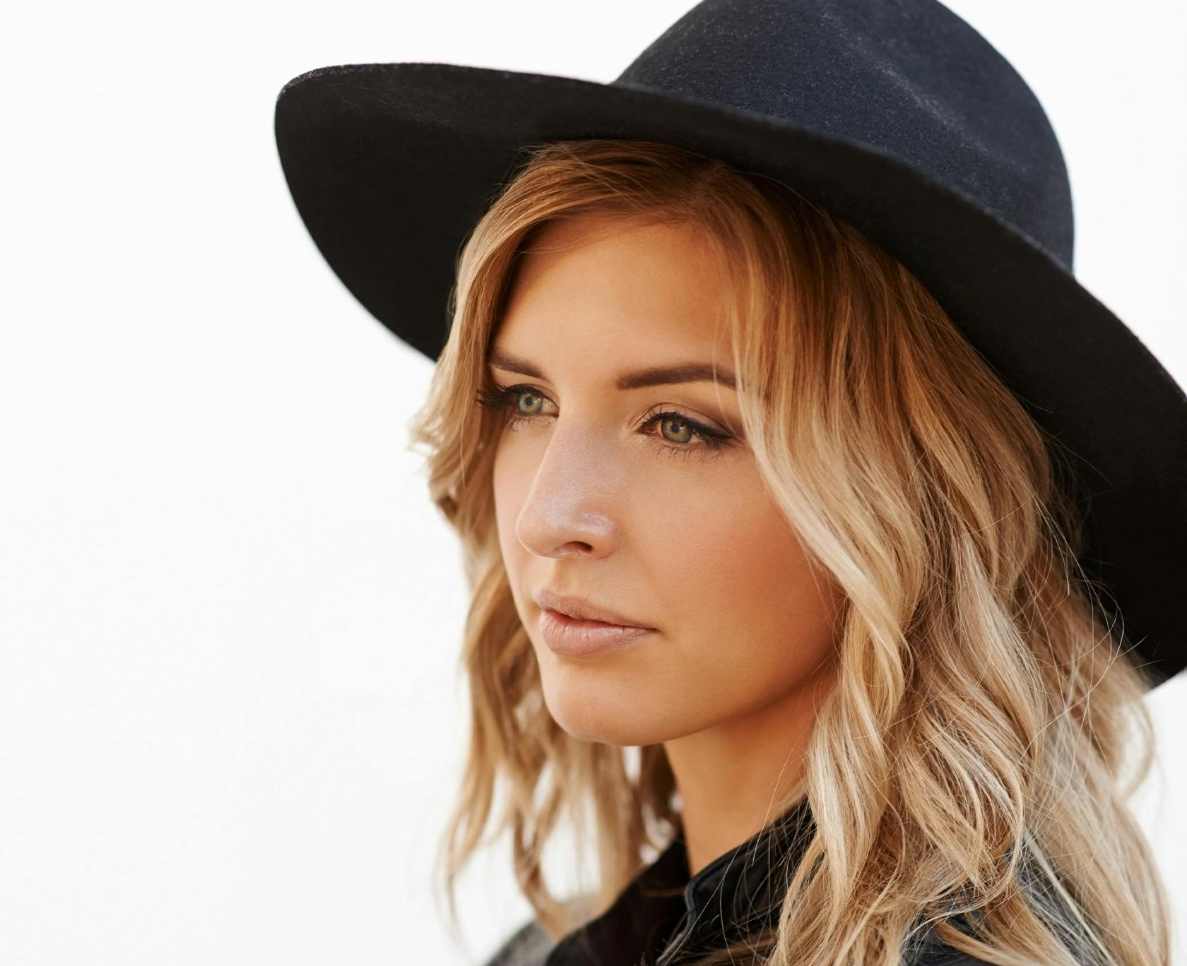 blond woman with black hat and black leather jacket looking at camera