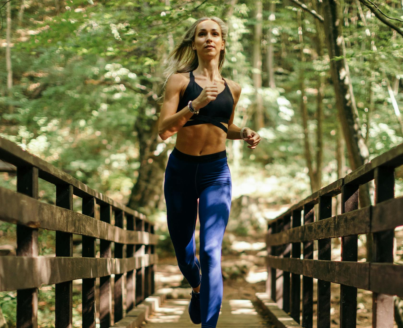woman running on a bridge in the woods