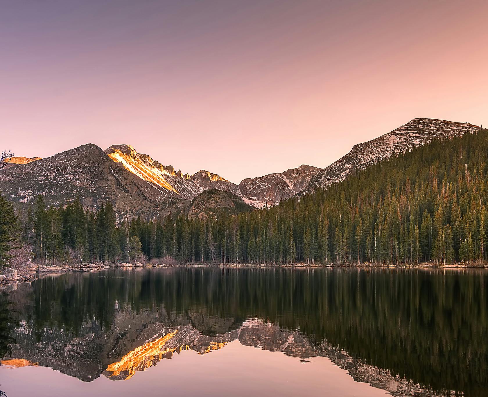 mountains reflected in a lake at sunset with a pink sky