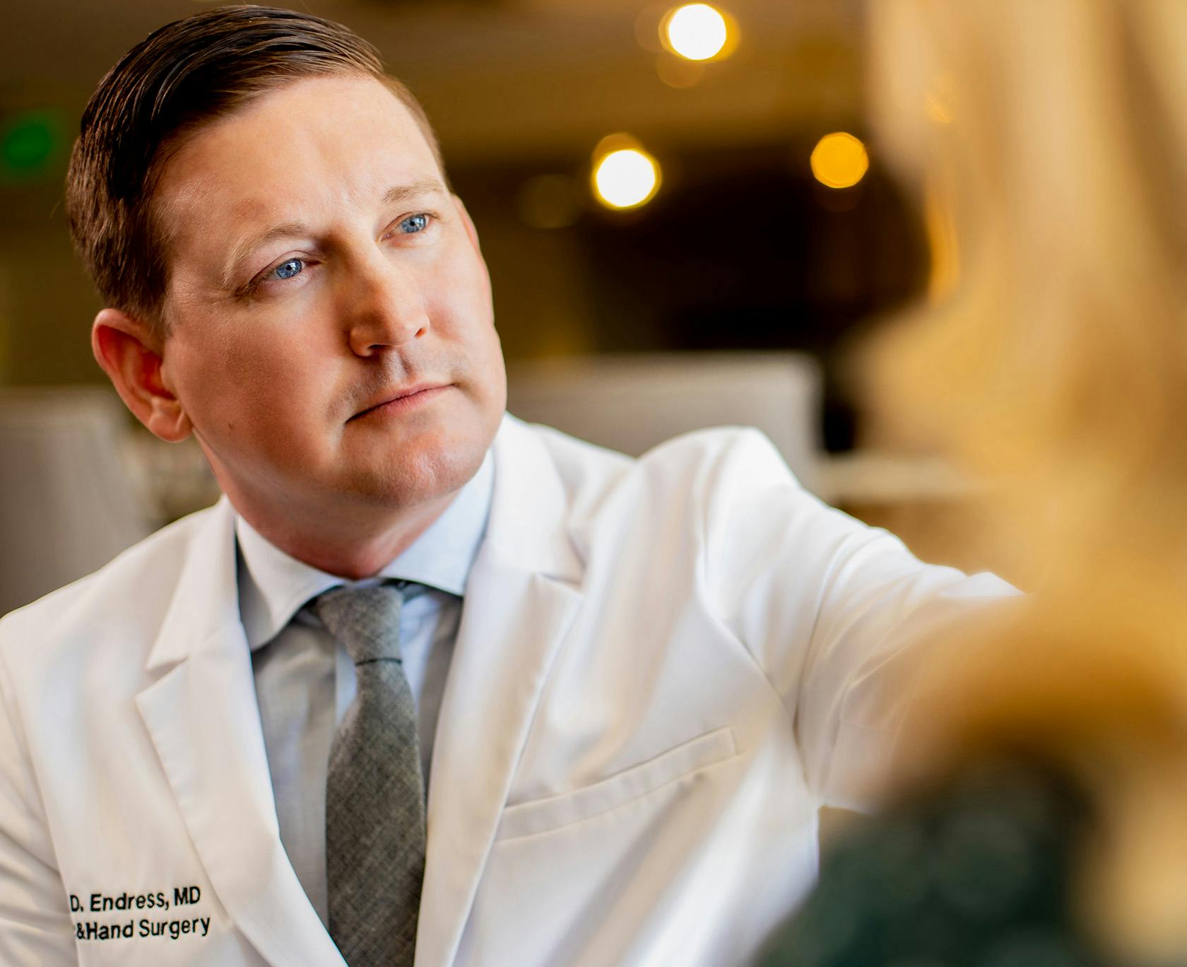 Dr. Ryan Endress with Lavie Institute in a white coat and tie looking at a patient