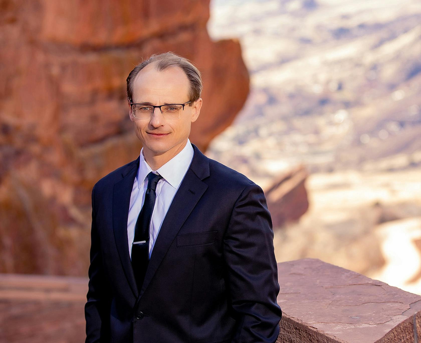 Dr. Wojciech Przylecki in a suit and tie standing on a ledge