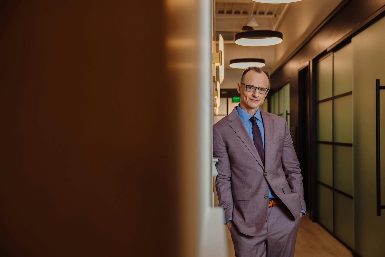 Dr. Wojciech Przylecki in suit leaning on wall