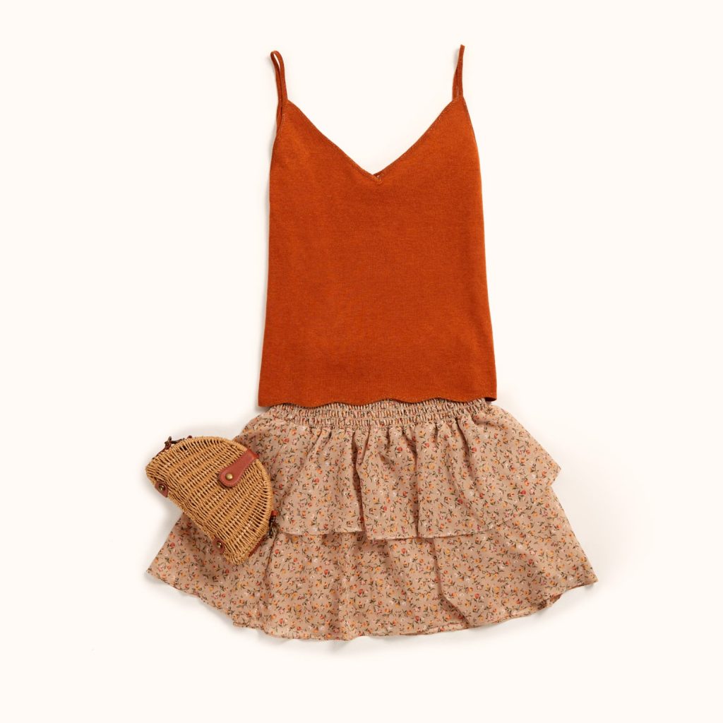 top de alças cor terra combinado com uma saia ligeira de folhos de padrão floral. 