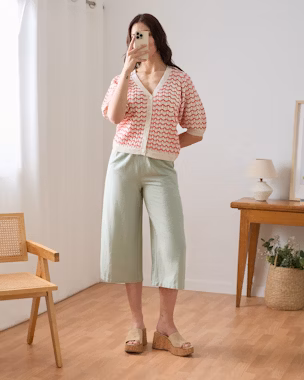 Long mint green bermuda paired with a red and white crochet top and beige platform sandals in a minimalist summer outfit.