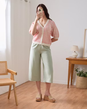 Long mint green bermuda paired with a red and white crochet top and beige platform sandals in a minimalist summer outfit.