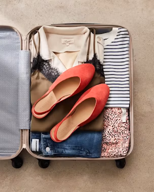 Open suitcase with basic clothes and red flats – perfect for packing based on trip length and destination